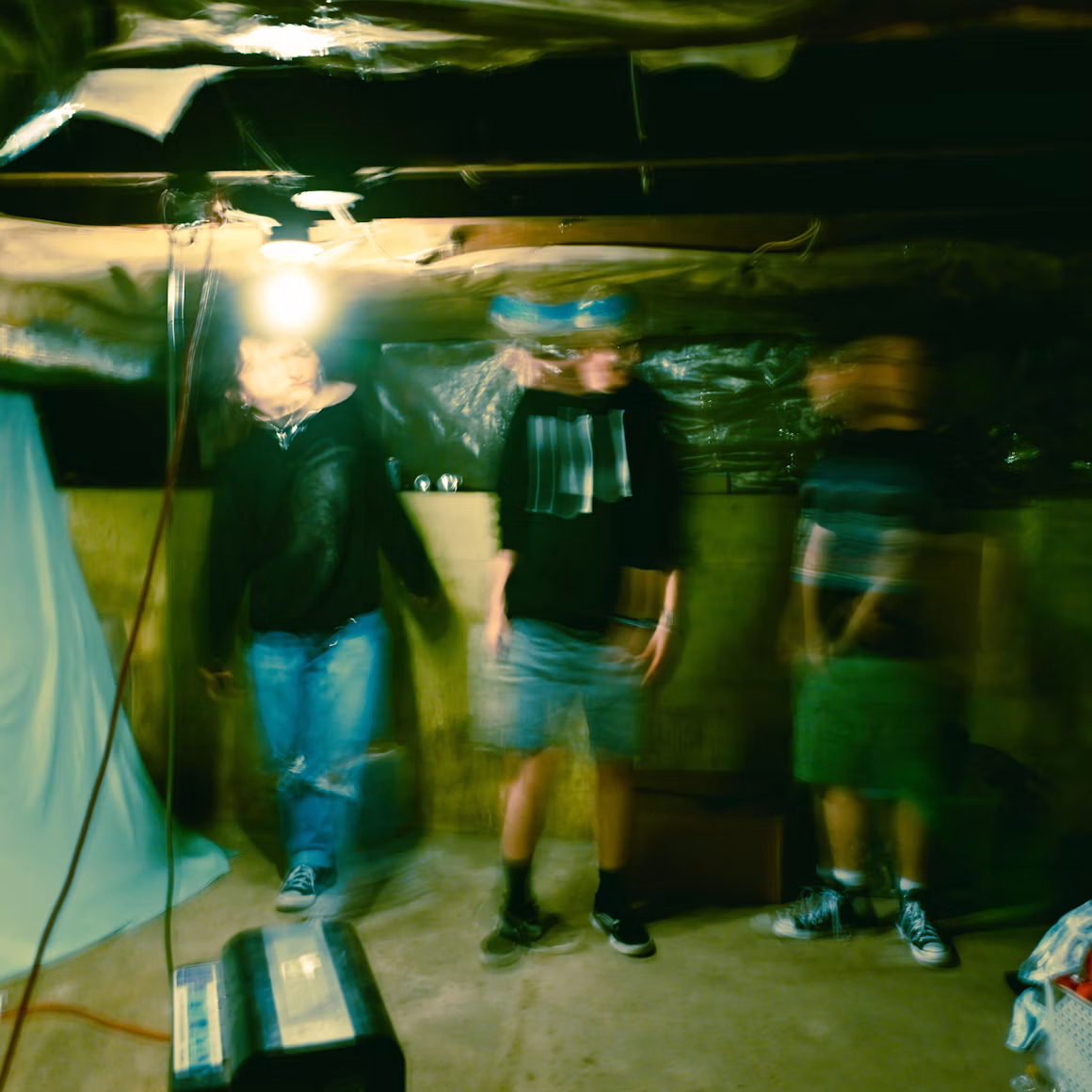 A blurred image of three people in a dark basement.